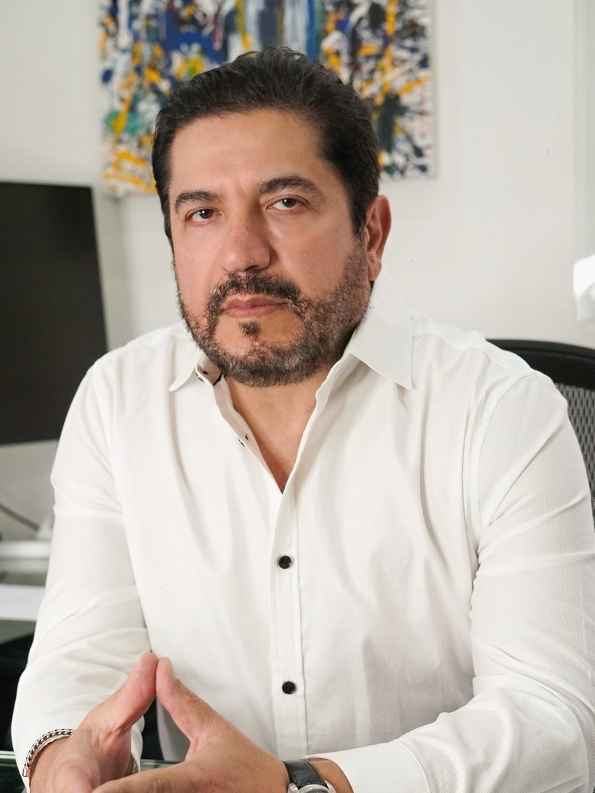 El Dr. Saad Barhoum en su escritorio, con las manos juntas, como en una consulta.